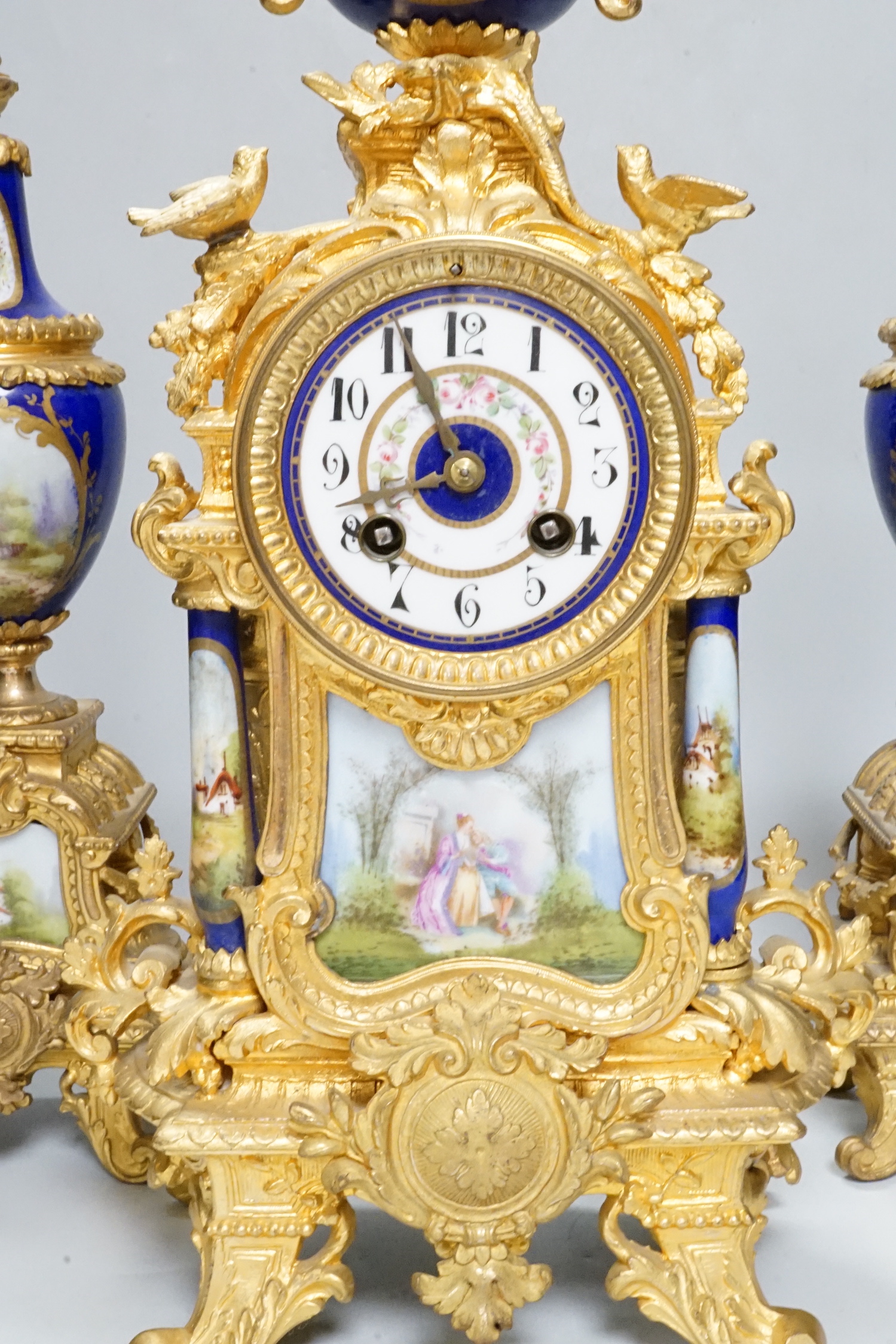 An early 20th century French gilt metal and porcelain set clock garniture, 42cm